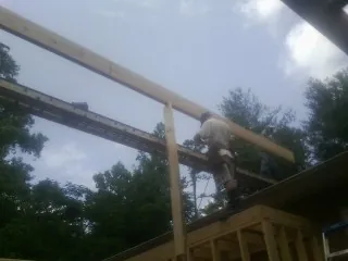 Carpenter setting a ridge beam over a new addition frame — Ice Dam Removal by Roofing Brothers in El Campo