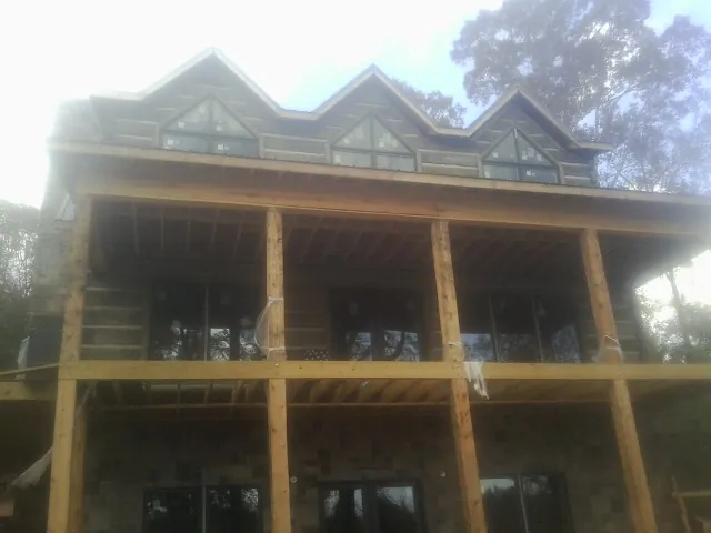 Dormers and porch framing on a large log home under construction — Roof Coating work by our crew in El Campo
