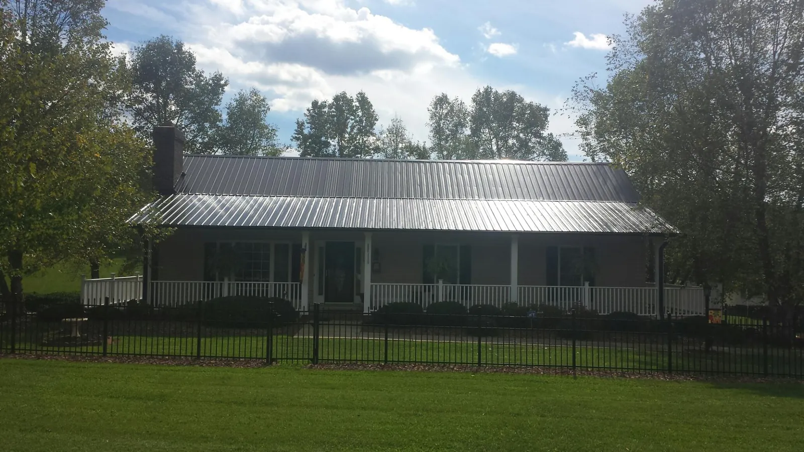 Gray metal roof on a brick ranch with a full width front porch — Gutter Guard Installation work by our crew in El Campo