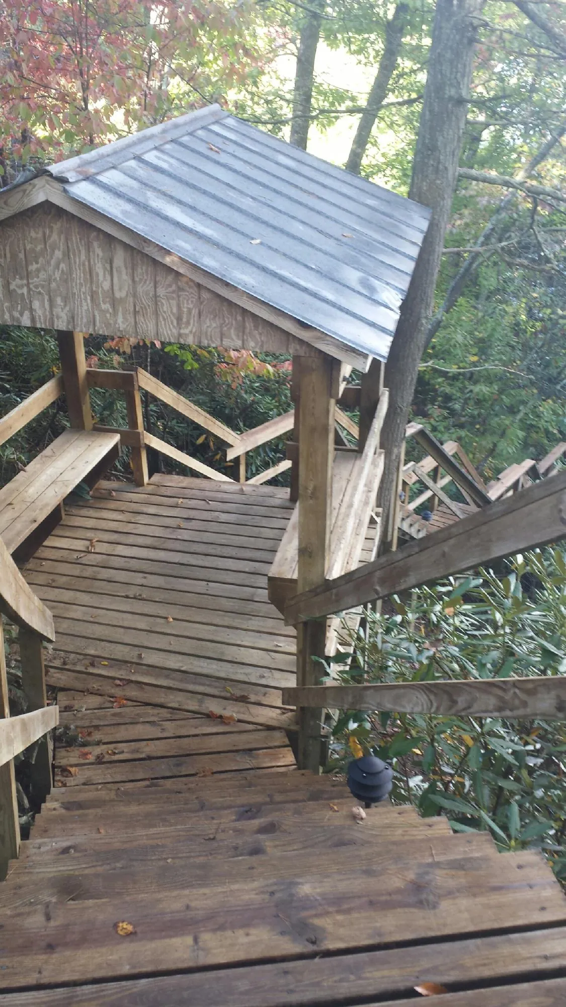 Metal roofed shelter over wooden steps on a wooded walkway — Skylight Repair & Installation work by our crew in El Campo