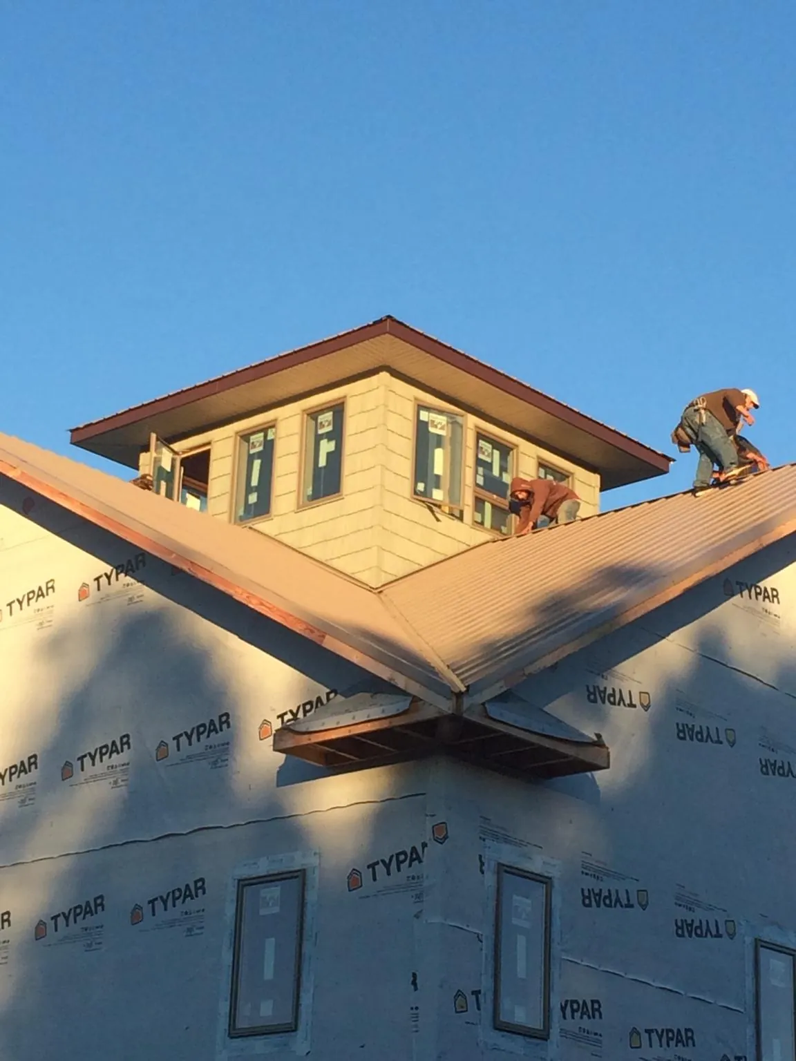 Roofers working around a rooftop cupola on a new metal roof at sunset — Roof Waterproofing in El Campo by Roofing Brothers